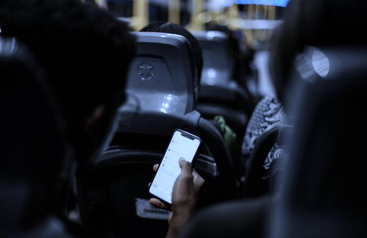 A person holding a smartphone in a dimly lit bus environment.