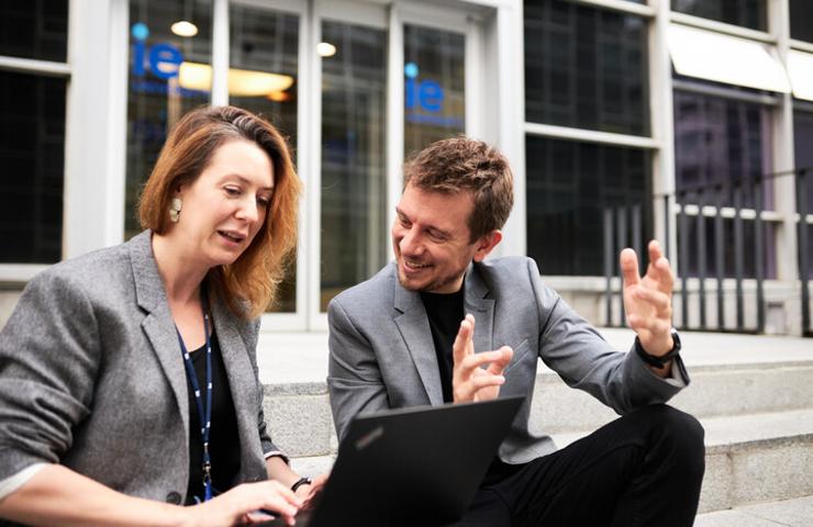 Two professionals engaged in a lively discussion while using a laptop.