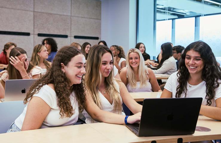 A group of students is engaged in a collaborative activity using laptops in a classroom.