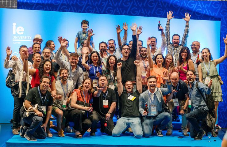 A vibrant group of people celebrating together with raised hands and smiles at an event.