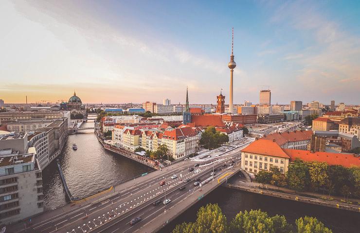 A panoramic view of Berlin showcasing its iconic buildings and waterways during sunset.
