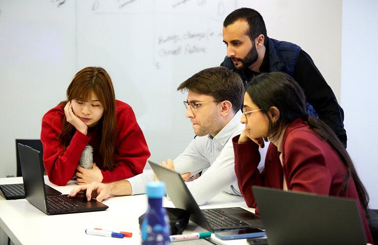 A group of young professionals collaborating on a project using laptops.