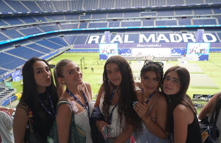 A group of five young women posing together at the Santiago Bernabéu Stadium.