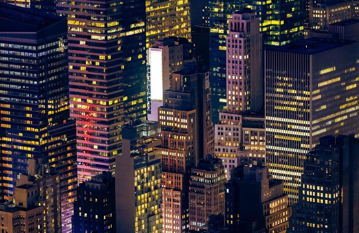 An aerial view of a city skyline at night, highlighting illuminated buildings and structures.