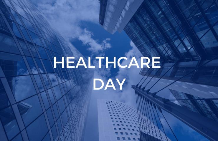 Looking up at a modern skyscraper with the text 'HEALTHCARE DAY' on a blue overlay.