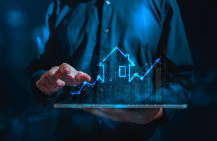 A person interacting with a holographic display of a house and rising graph.
