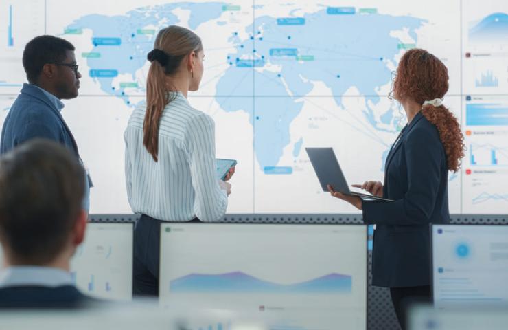 Business professionals analyzing data on large digital screens in a high-tech office.