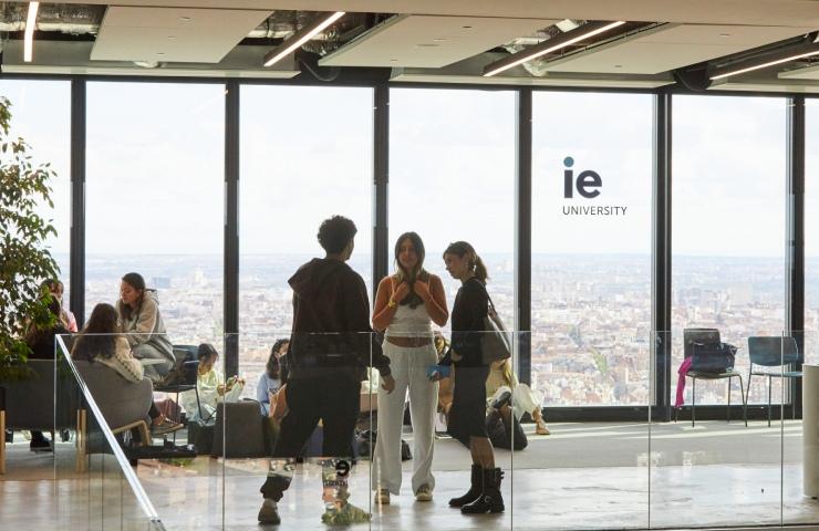 A group of students interacting in a modern university setting with a city view.