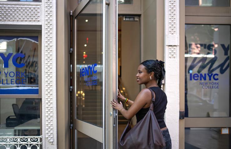 A woman is entering the New York College building.