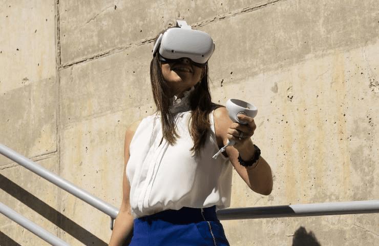 A woman wearing a virtual reality headset, holding a controller while standing on stairs.