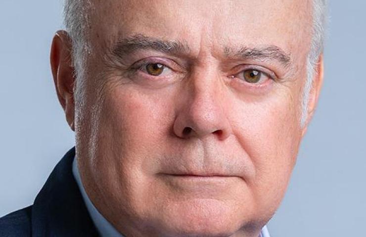 Close-up portrait of an elderly man with grey hair and serious expression, wearing a suit.