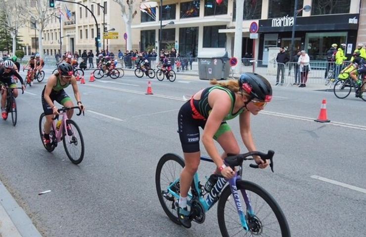 Female athletes competing in a cycling race on an urban road.