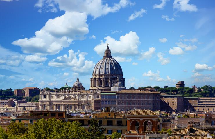 A panoramic view of St. Peter's Basilica in Vatican City under a bright blue sky.