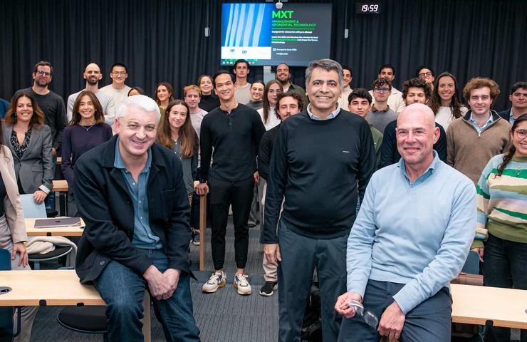 A group of people posing for a photo in a classroom setting with a presentation screen in the background.
