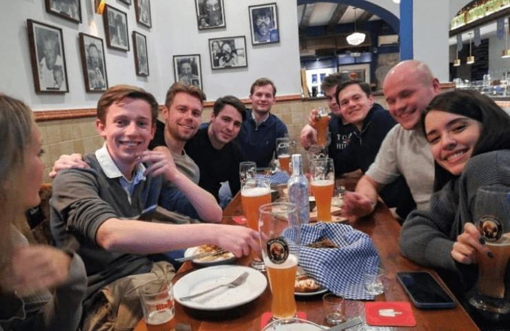 A group of friends enjoying a meal together at a pub with drinks on the table.