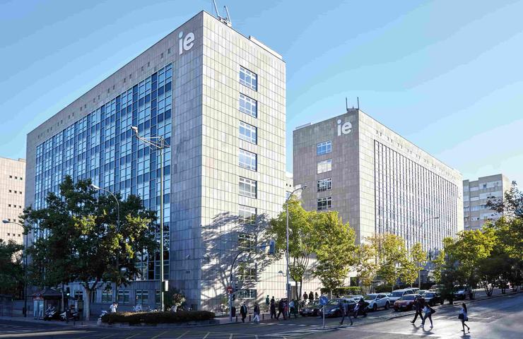 The image shows modern buildings with large glass facades and the letters 'ie' prominently displayed.