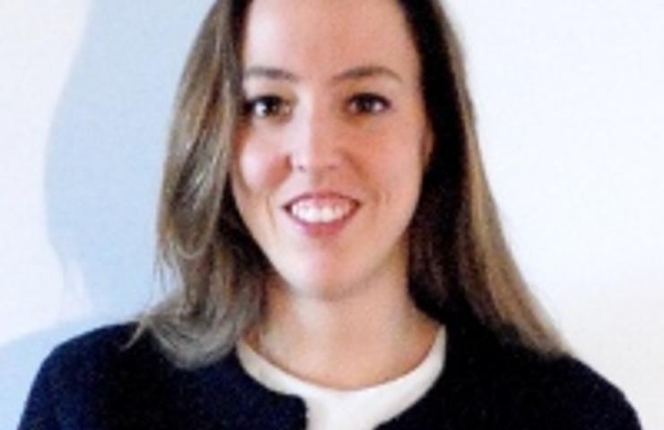 A professional woman smiling in a business attire against a plain background.