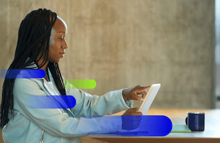 A woman with braided hair is interacting with a tablet at a modern workspace.