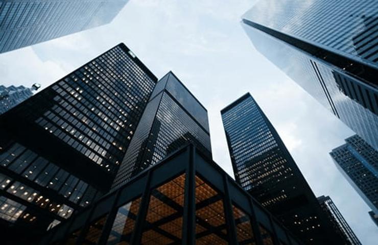 A low-angle view of modern skyscrapers under a cloudy sky.