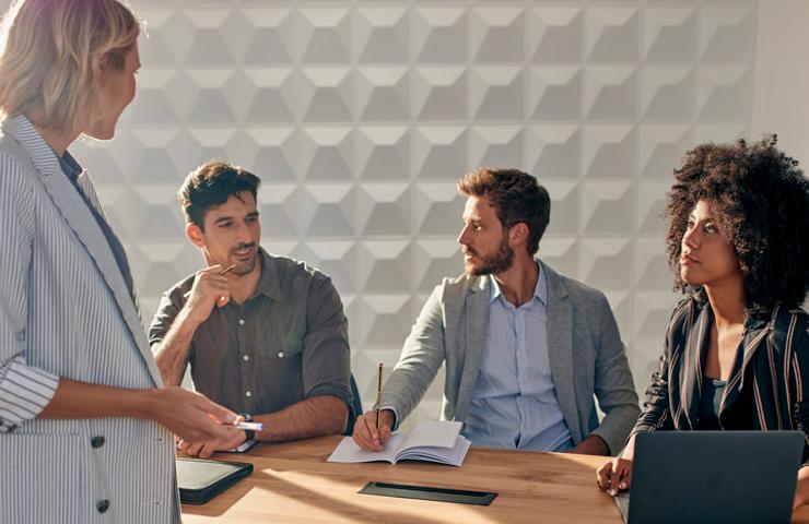 A group of four people engaged in a business meeting around a table.