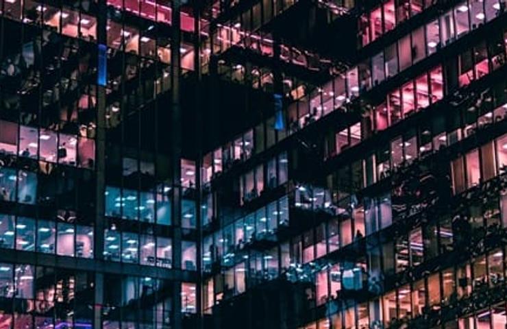A modern building facade illuminated in vibrant colors at night.