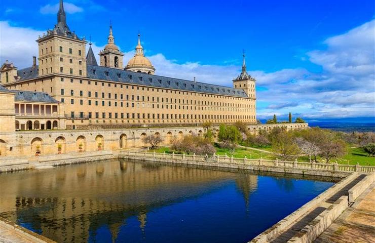 A stunning view of a historical monastery by a serene water body under a clear blue sky.