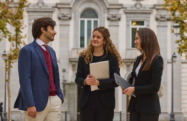 Three professionals engaged in conversation outdoors in a city setting.