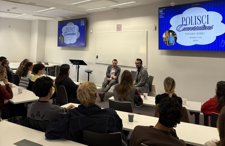 A classroom setting with students engaged in a discussion with two speakers on a panel.