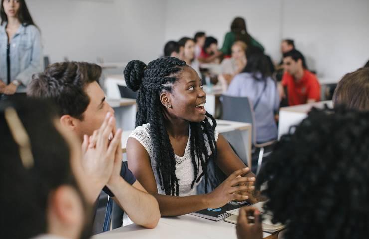 A diverse group of students engaged in discussion in a classroom setting.