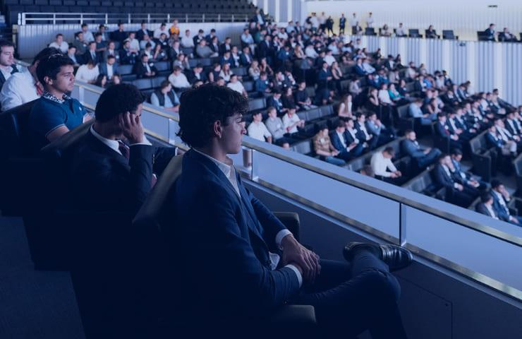 A group of people seated at a conference, attentively listening to the speaker.