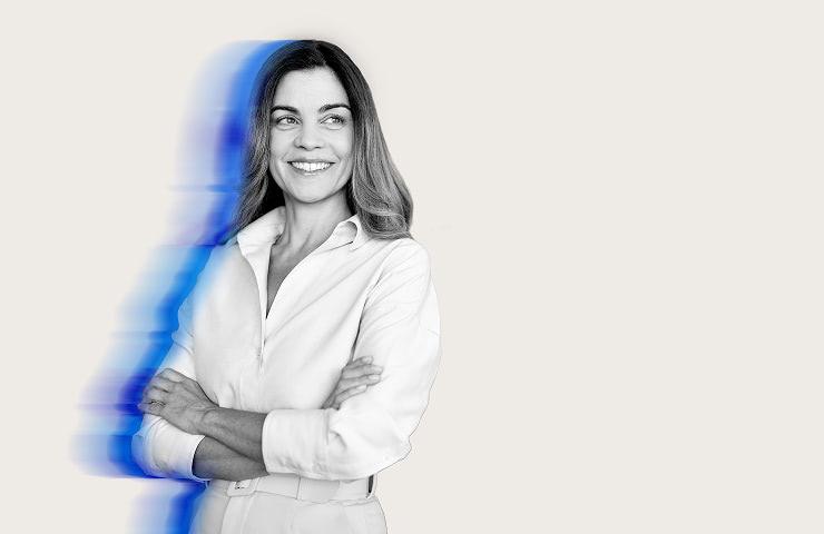 A smiling woman in a white shirt with a blurred blue effect beside her.