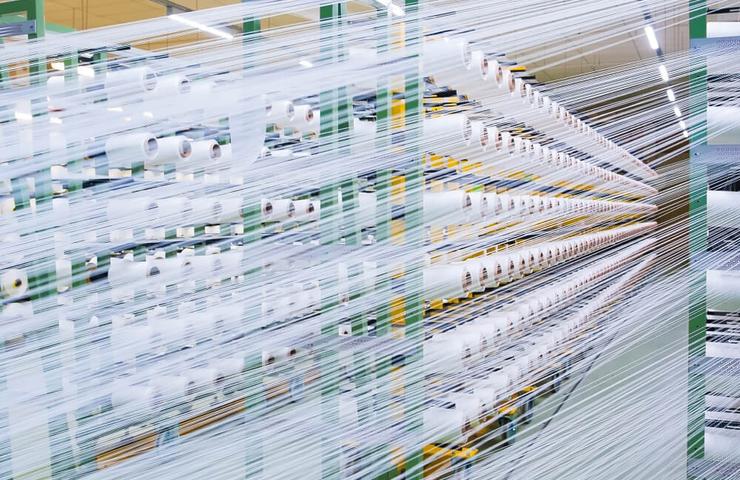 Long exposure shot of a busy textile factory with rows of fabric production machinery.