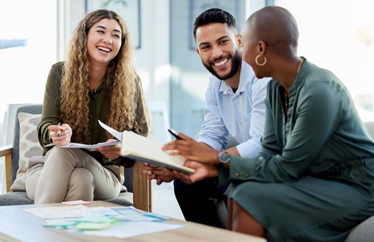 Three professionals sitting and discussing with documents on a table in a well-lit office.