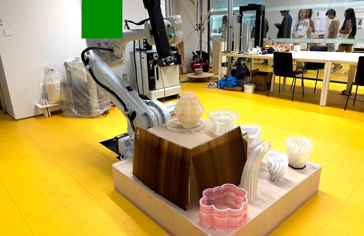 A robotic arm is working in a modern studio, surrounded by various decorative objects.
