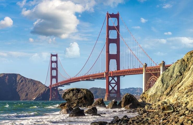 A majestic view of the Golden Gate Bridge against a backdrop of clouds and water.