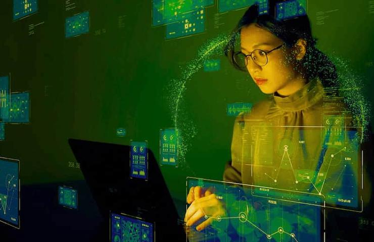 A woman analyzes data on multiple computer screens in a high-tech, digital environment.