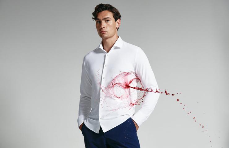 A man in a white shirt with a dynamic red splash design across it, posing on a grey background.