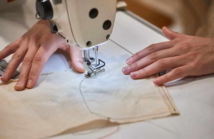 A person sewing with a sewing machine on a piece of fabric.