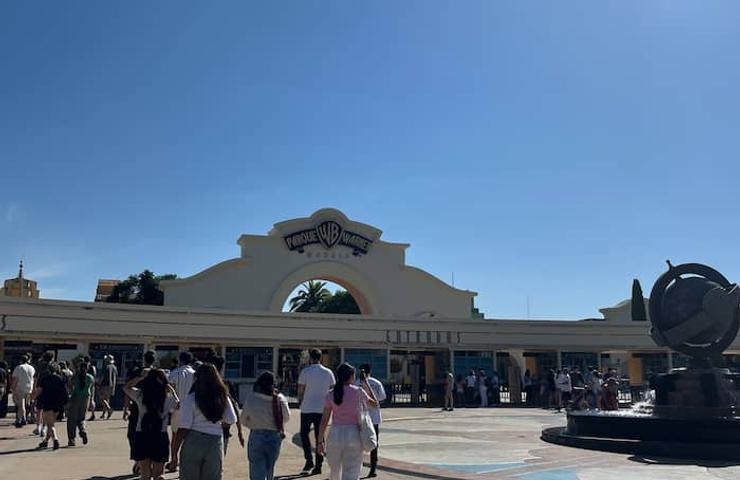 People walking towards a modern building entrance under a clear blue sky.