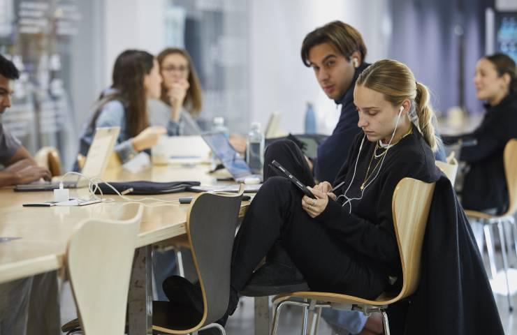 Young adults are working and using electronic devices at a modern office table.