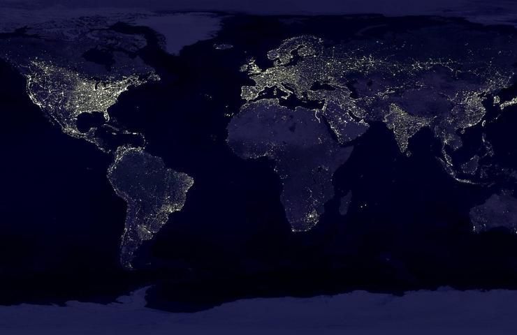 A satellite image of Earth at night showing the illuminated areas of human habitation.