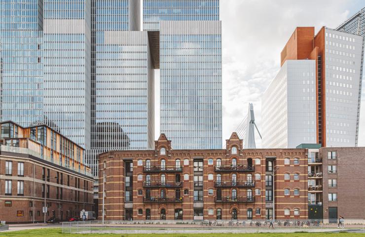 Old brick building juxtaposed against modern skyscrapers under a cloudy sky.