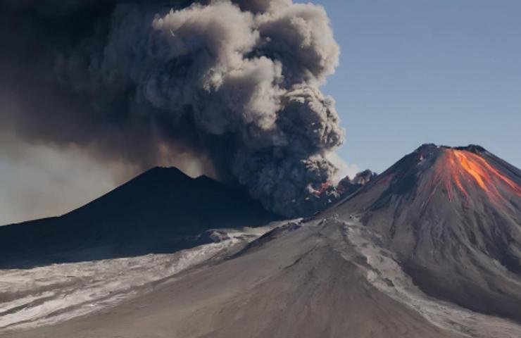 A volcanic eruption with thick smoke and lava glowing from the peak.