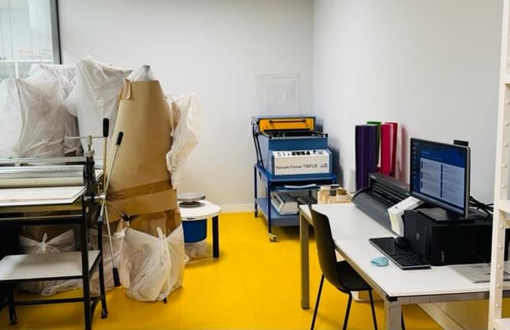 A cluttered workspace featuring various machines and supplies.