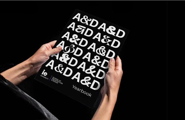 A person is holding a yearbook featuring a bold typographic cover design.