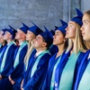 A group of graduates wearing blue caps and gowns, looking upward during a ceremony.