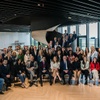 A large group of people posing for a photo in a modern office space.