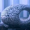 A large, futuristic sculpture featuring intricate calligraphy in an urban setting.