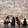 A group of people is admiring a large mural in an art gallery.