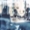 A blurred view of people engaged in a meeting around a table.
